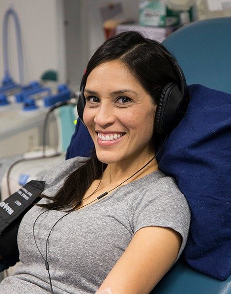 Person wearing headphones, sitting in cot donating platelets