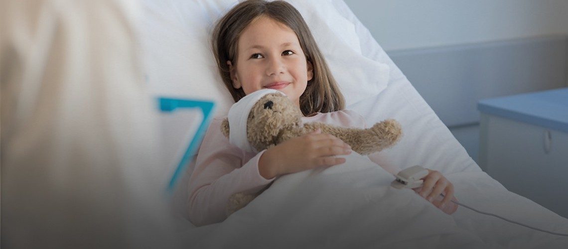 Child in bed holding a teddy bear.
